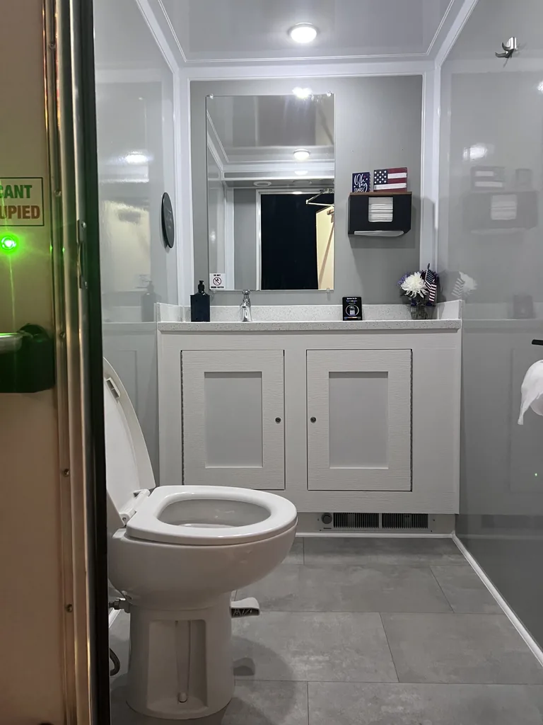 Climate-controlled restroom trailer interior with vanity lighting and vacant indicator